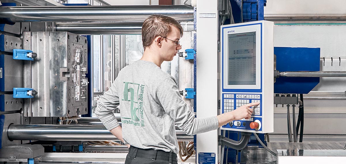 Mitarbeiter produziert Spritzgussbauteile an Maschine